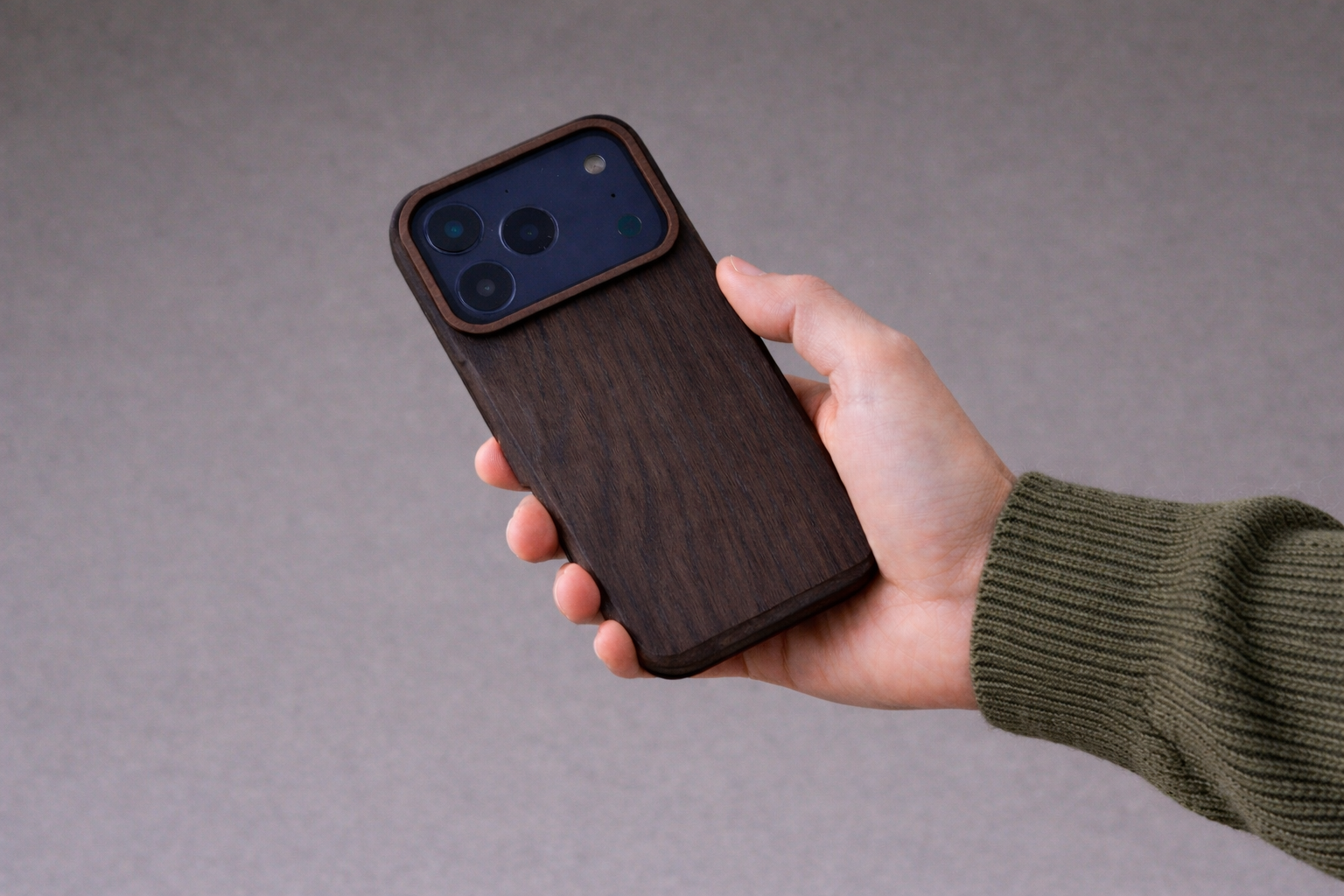 smartphone mit dunkler Holz-Hülle wird in einer Hand gehalten